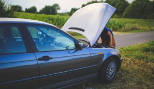 Car breakdown situation requiring roadside assistance in rural area with hood open