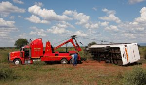 Winch out service assists overturned vehicle in rural area under clear blue sky